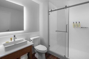 A modern bathroom with a white sink, toilet, and glass shower enclosure.