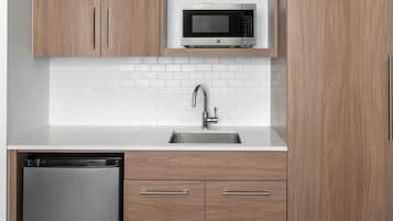 Una cocina moderna con armarios de madera, un lavamanos de acero inoxidable y un microondas empotrado.