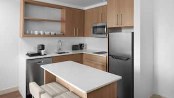 Una cocina moderna con armarios de madera, un refrigerador de acero inoxidable, un microondas y un lavavajillas.