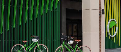 Two bicycles parked in front of a building with a green facade and a circular logo.