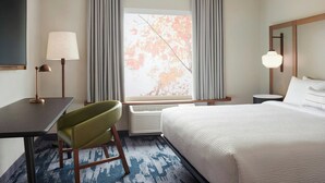 Una camera d'hotel con un letto, una scrivania, una sedia, una lampada, una finestra con tende e un termosifone.