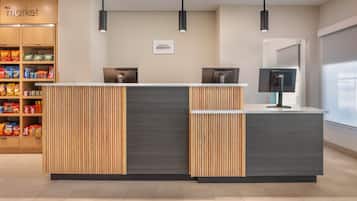 A hotel reception desk with a modern design, featuring a wooden panel and a grey counter.