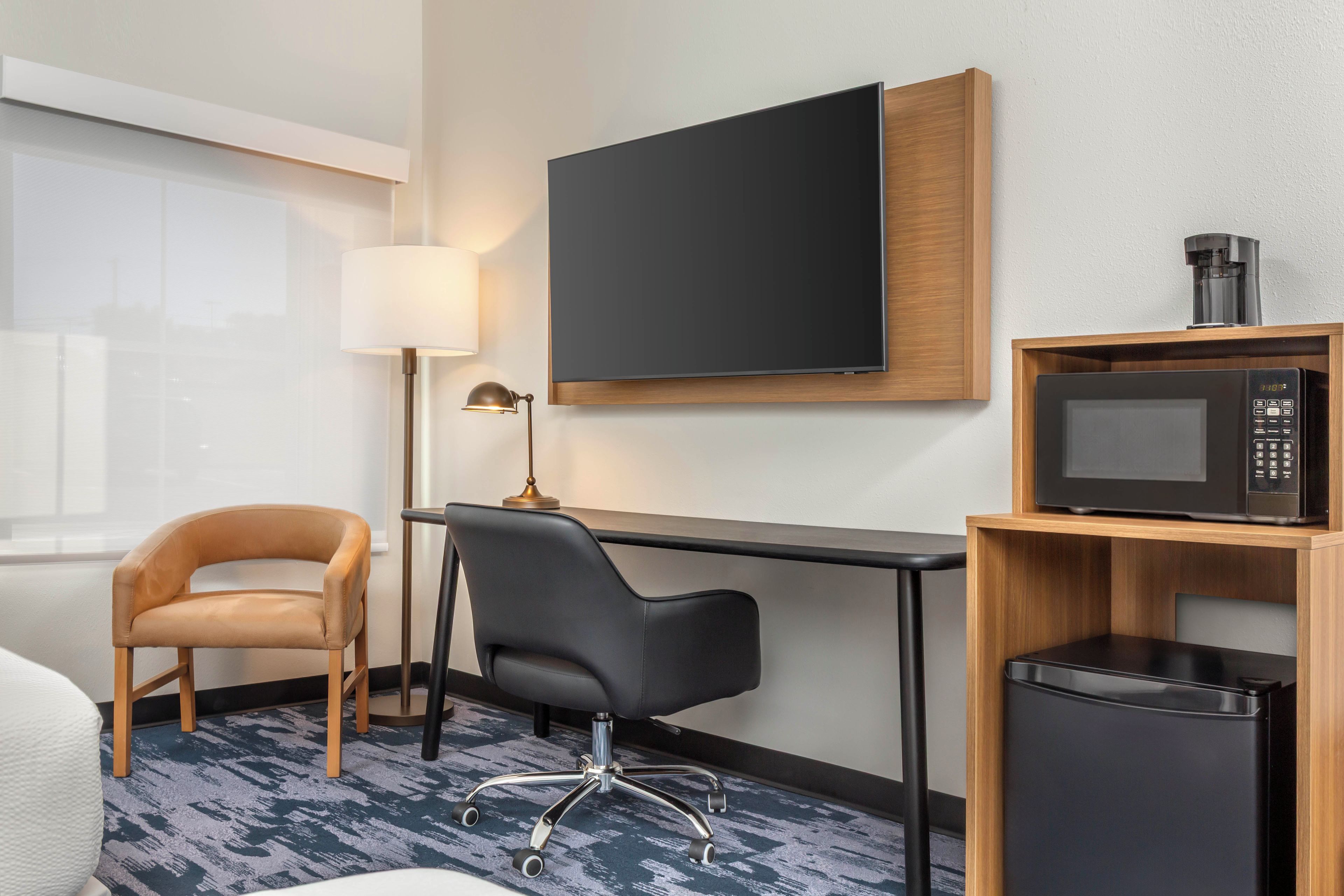Une chambre d’hôtel équipée d’un bureau, d’une chaise, d’une télévision, d’une machine à café et d’un four à micro-ondes.