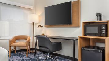 Une chambre d’hôtel équipée d’un bureau, d’une chaise, d’une télévision, d’une machine à café et d’un four à micro-ondes.