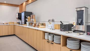 A modern kitchen area with a coffee machine, a waffle maker, and various food containers.