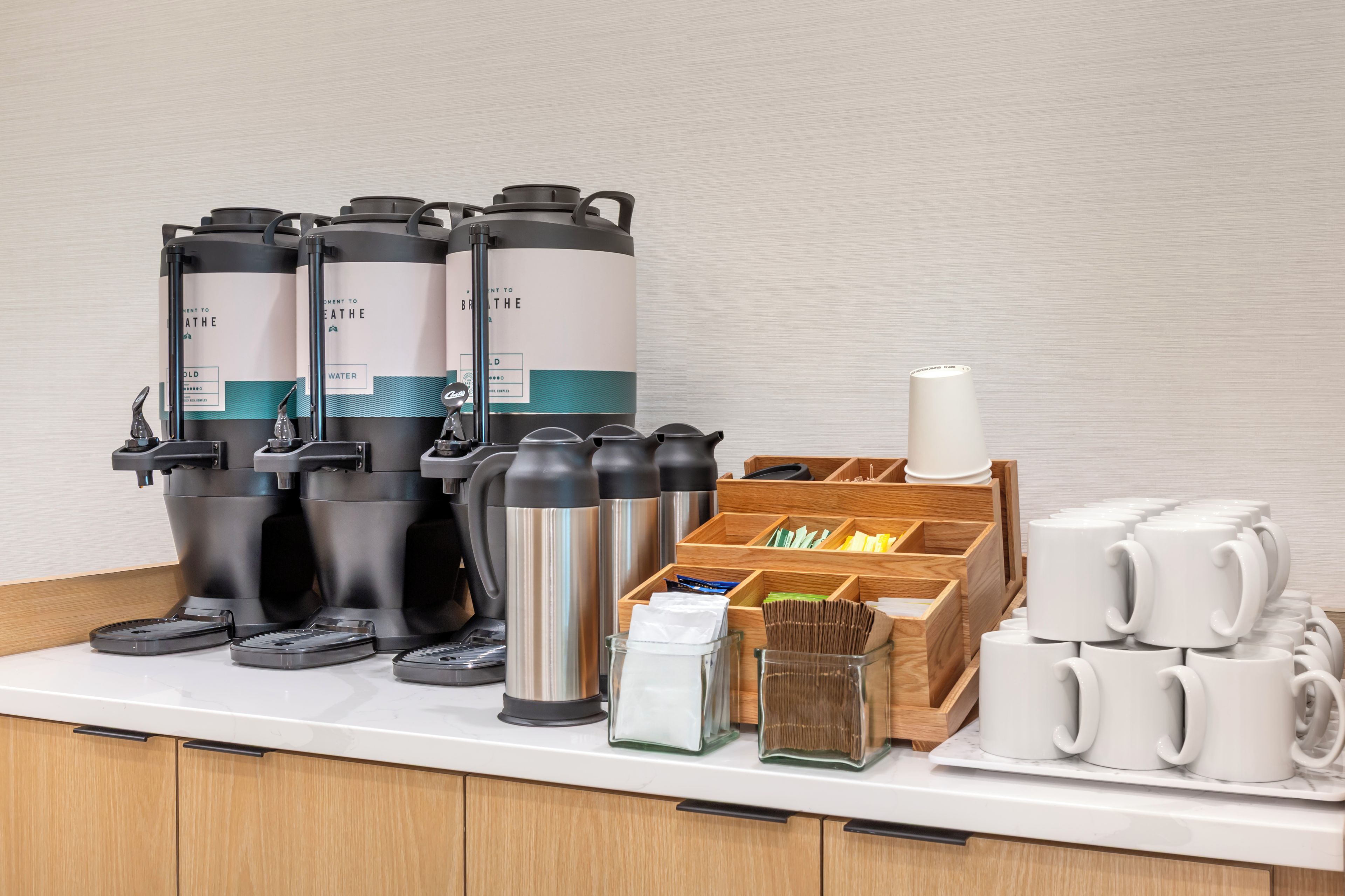 En kaffestation med flere dispensere, en kaffepande og en kopholder.
