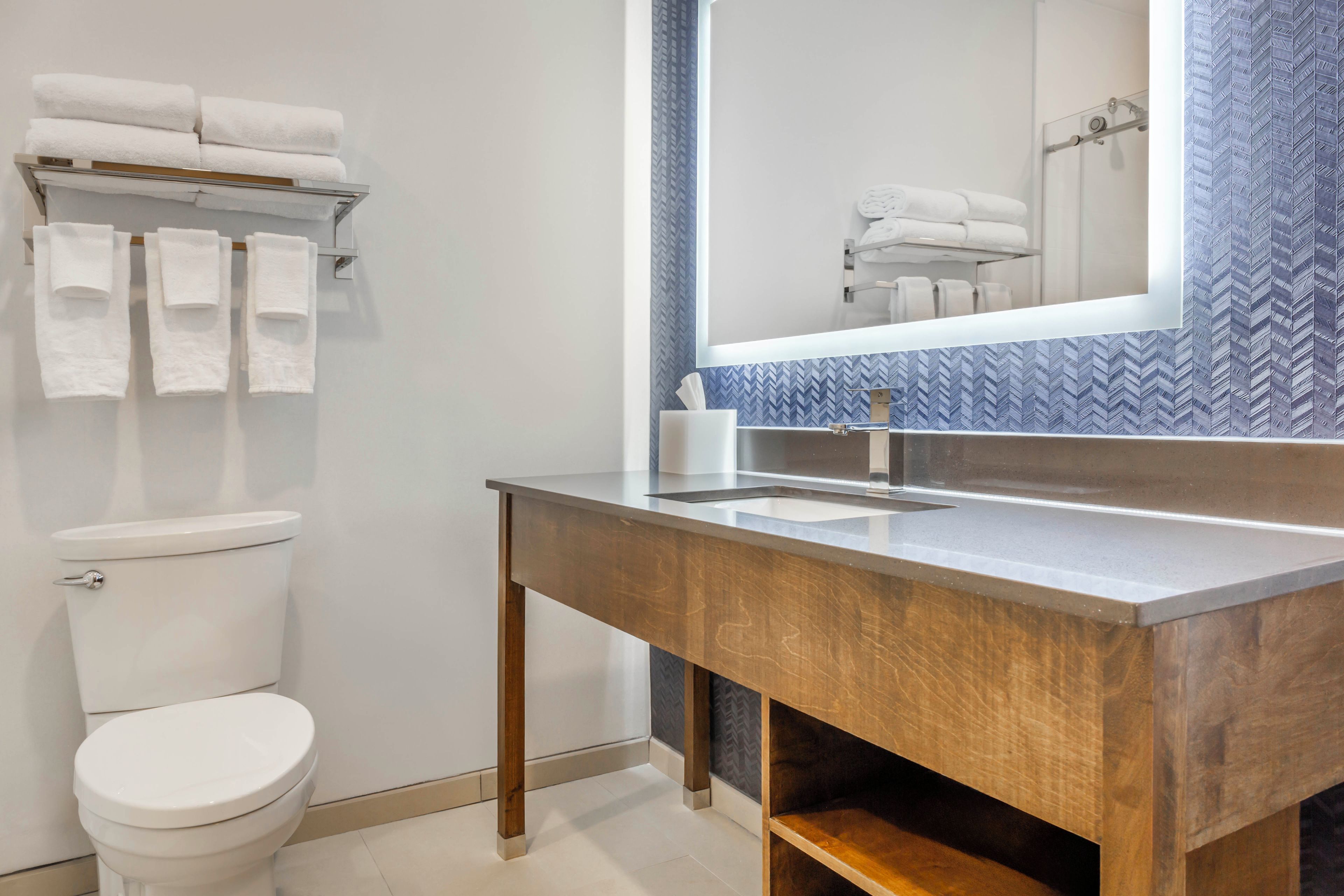 A modern bathroom with a toilet, a sink, and a mirror.