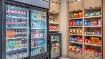 A beverage cooler stocked with various drinks and a snack shelf with assorted packaged foods.