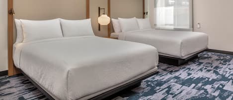 A hotel room with two beds, a large window, and a modern light fixture.