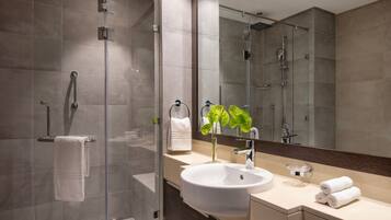 A modern bathroom with a glass shower enclosure, a large sink, and a mirror.