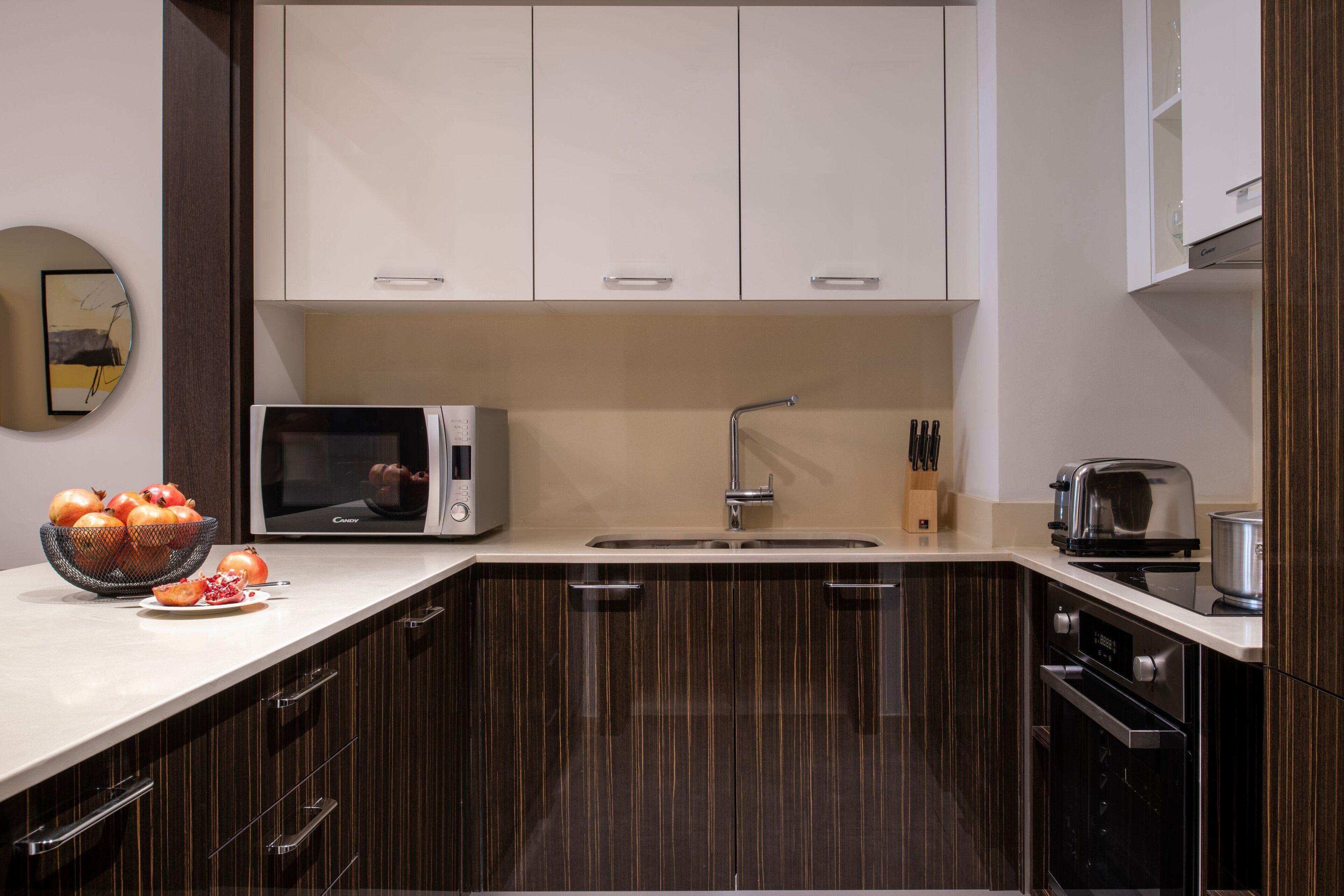 Eine moderne Küche mit dunklen Holzschränken, einer Mikrowelle, einem Toaster und einem Spülbecken.