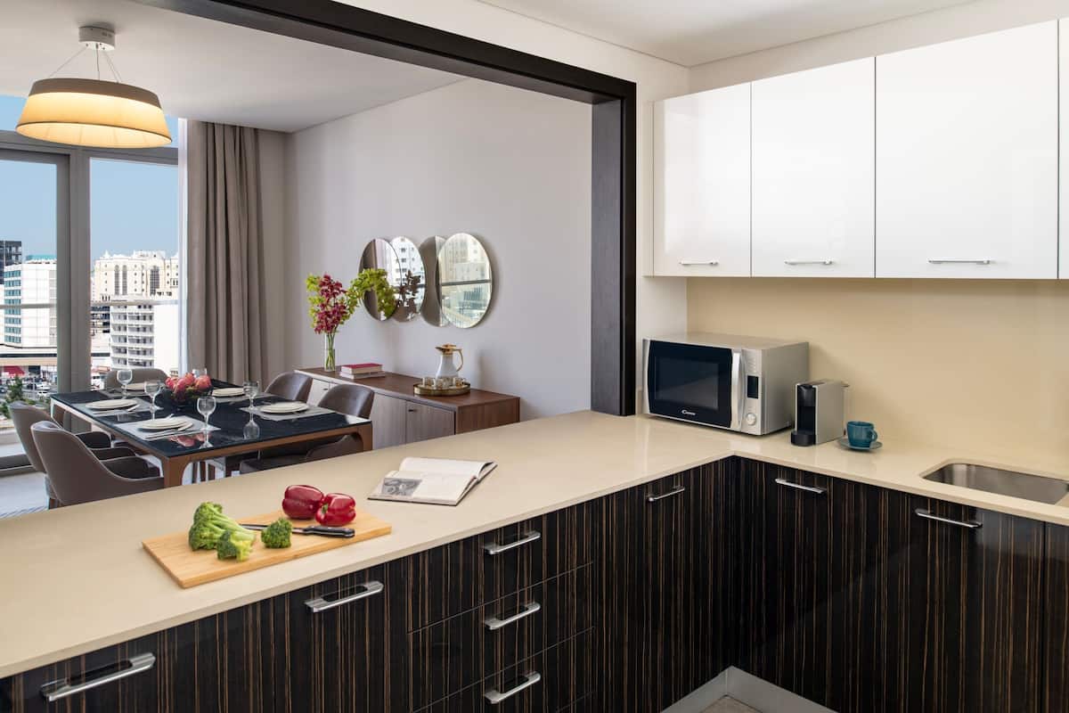 A modern kitchen with a dining area, large windows, and a city view.