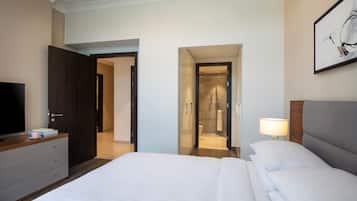 A hotel room with a large bed, a TV on a dresser, a walk-in closet, and a shower area.