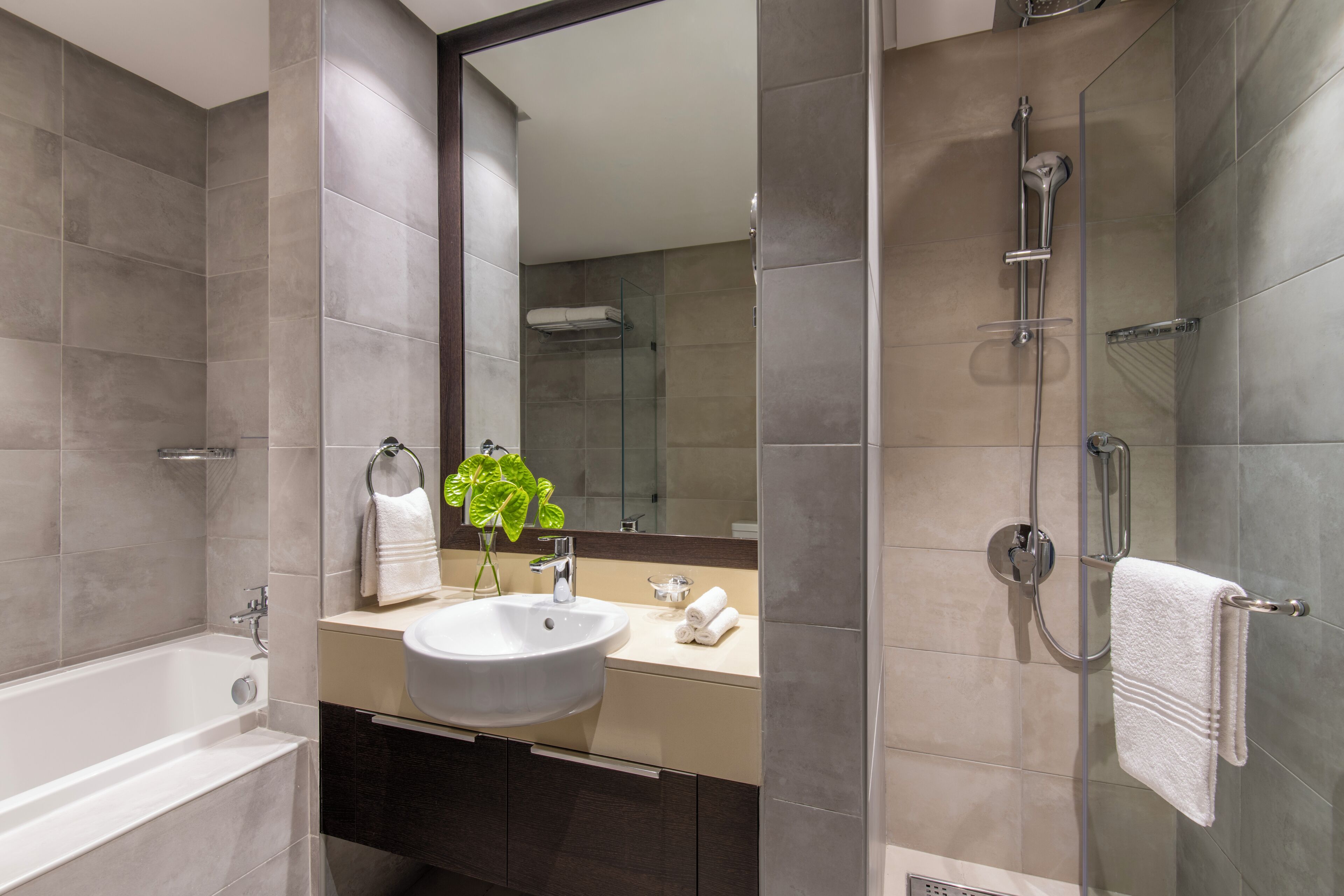 Un baño moderno con bañera, lavabo y ducha con mampara de vidrio.