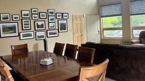 Un'area pranzo con un tavolo e sedie in legno, un divano e una parete decorata con quadri.