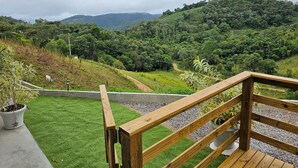 A wooden deck with a view of a lush green landscape and distant hills. - Refúgio da Montanha - Angelina - SC (Angelina)