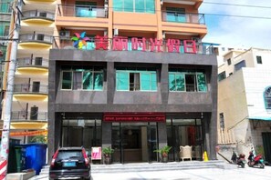 A multi-story building with a prominent sign and a car parked in front.
