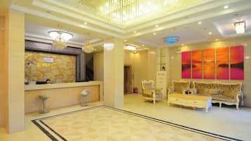 A hotel lobby with a reception desk, seating area, and a large abstract painting on the wall.