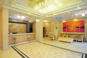A hotel lobby with a reception desk, seating area, and a large abstract painting on the wall.