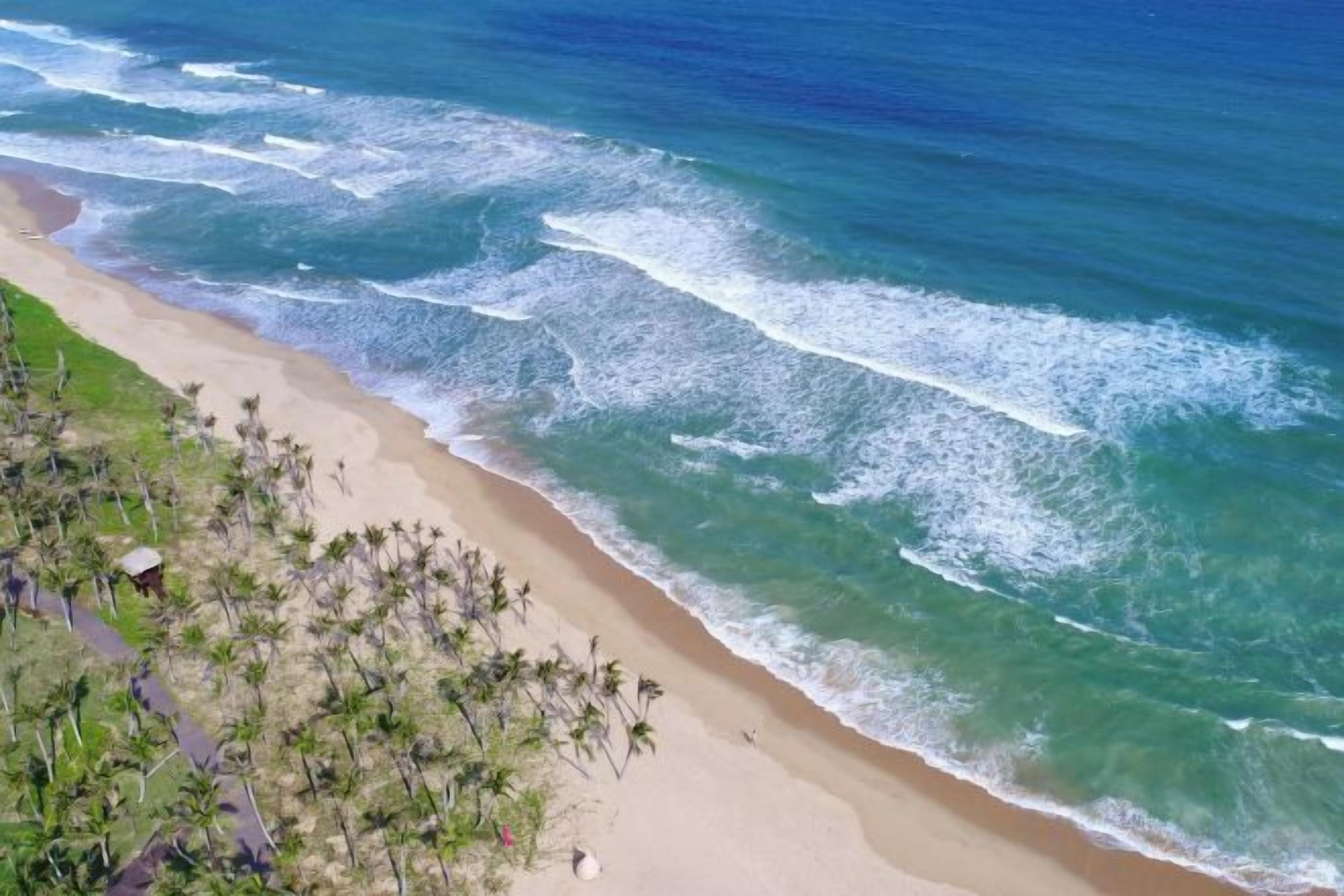 A beach with clear blue water and a sandy shore.