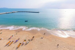 Ein Strand mit angeordneten Booten und einer anlegenden Mole.