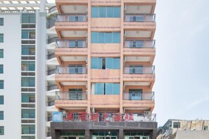 A multi-story building with balconies and a sign indicating a business or commercial establishment.