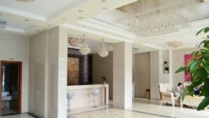 A spacious lobby with a reception desk, seating area, and a chandelier.