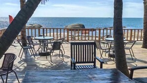 An outdoor seating area with tables and chairs, overlooking the ocean.