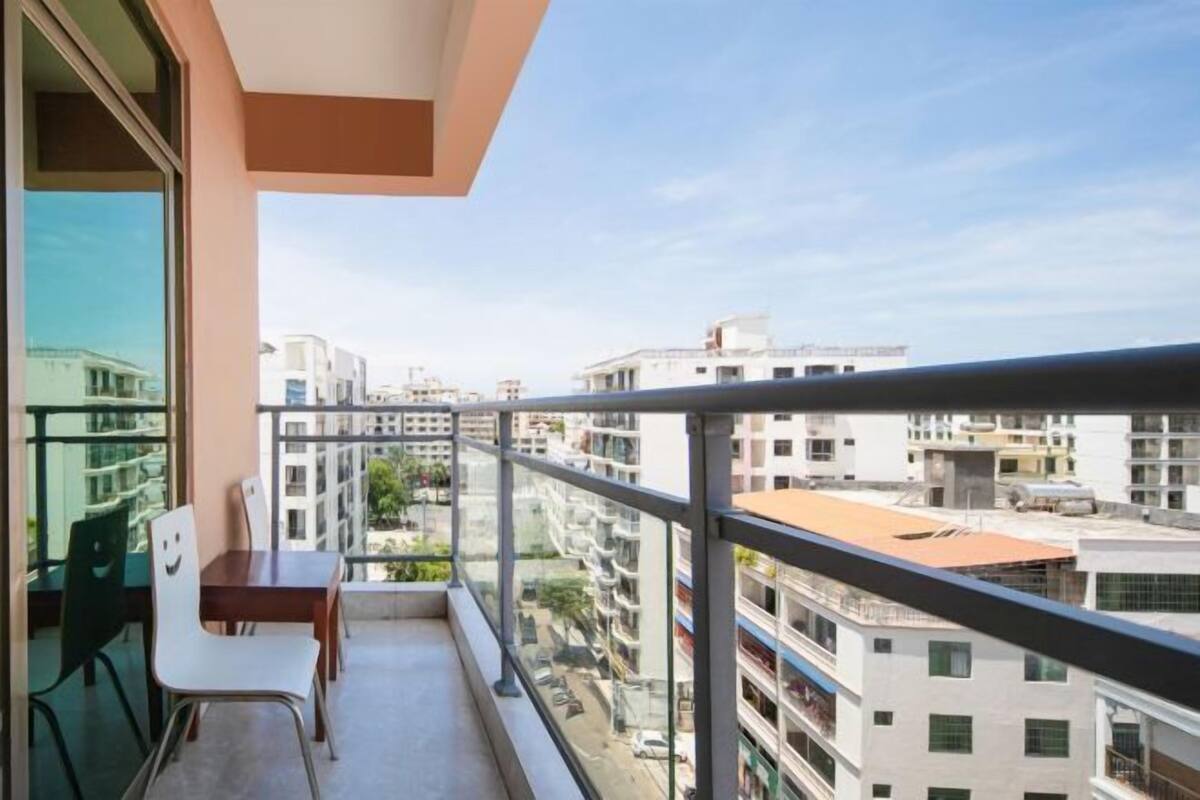 Varanda com mesa e cadeiras, vista para um horizonte urbano com vários edifícios.