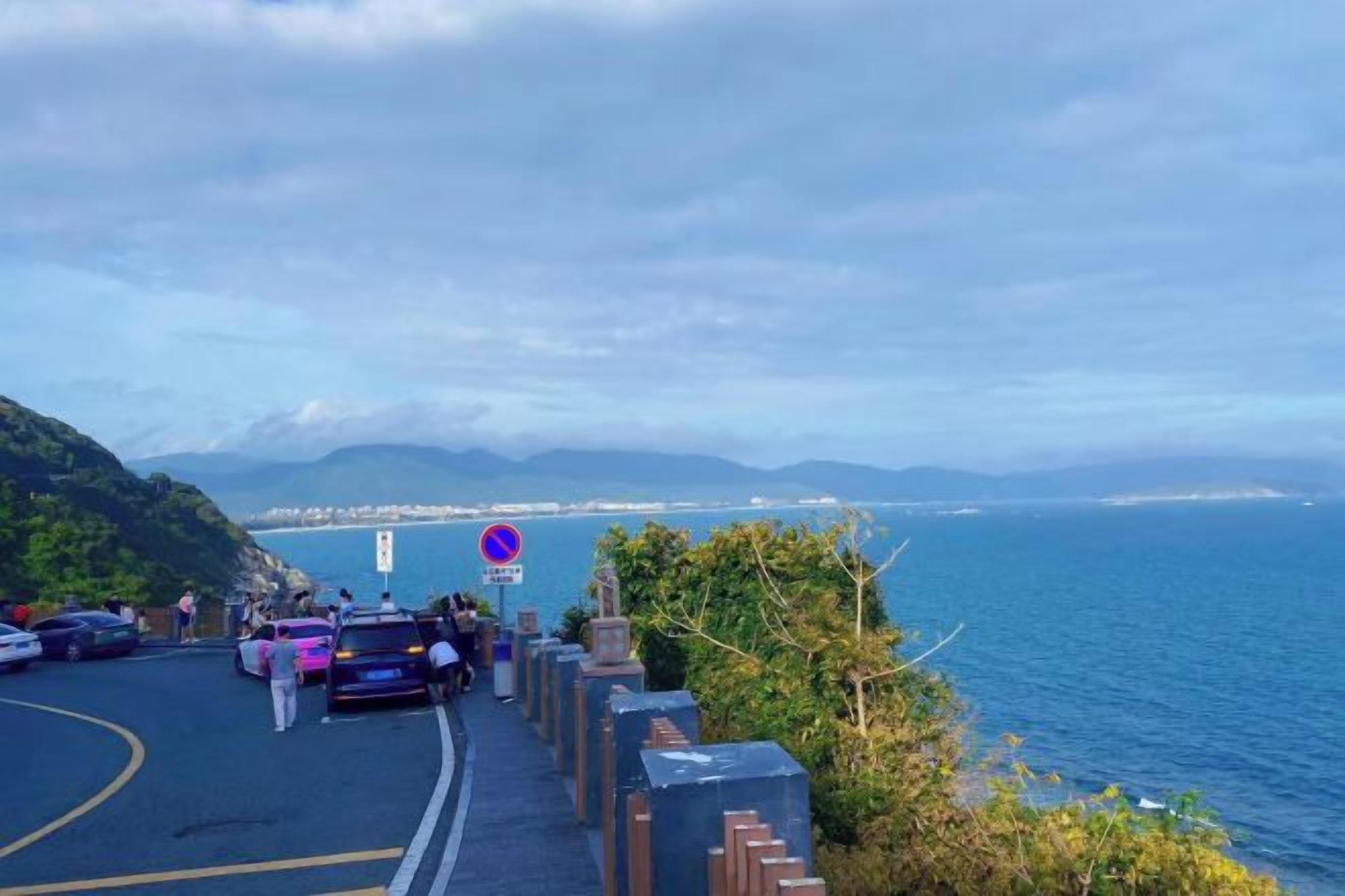 A coastal road with a view of the sea and distant mountains.