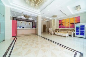 A hotel lobby with a reception desk, seating area, and a large painting on the wall.