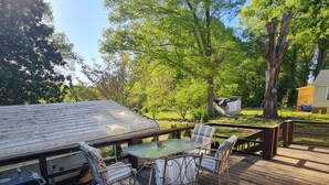 A wooden deck with a glass table and chairs, surrounded by trees and a small shed. - Holmes Residence (Taylorsville)