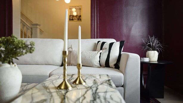 Una sala de estar moderna con un sofá blanco, una mesa de centro de mármol y una mesita auxiliar con una planta.