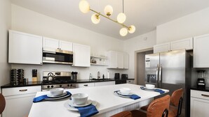 Una cocina moderna con armarios blancos, electrodomésticos de acero inoxidable y una isla central con asientos.