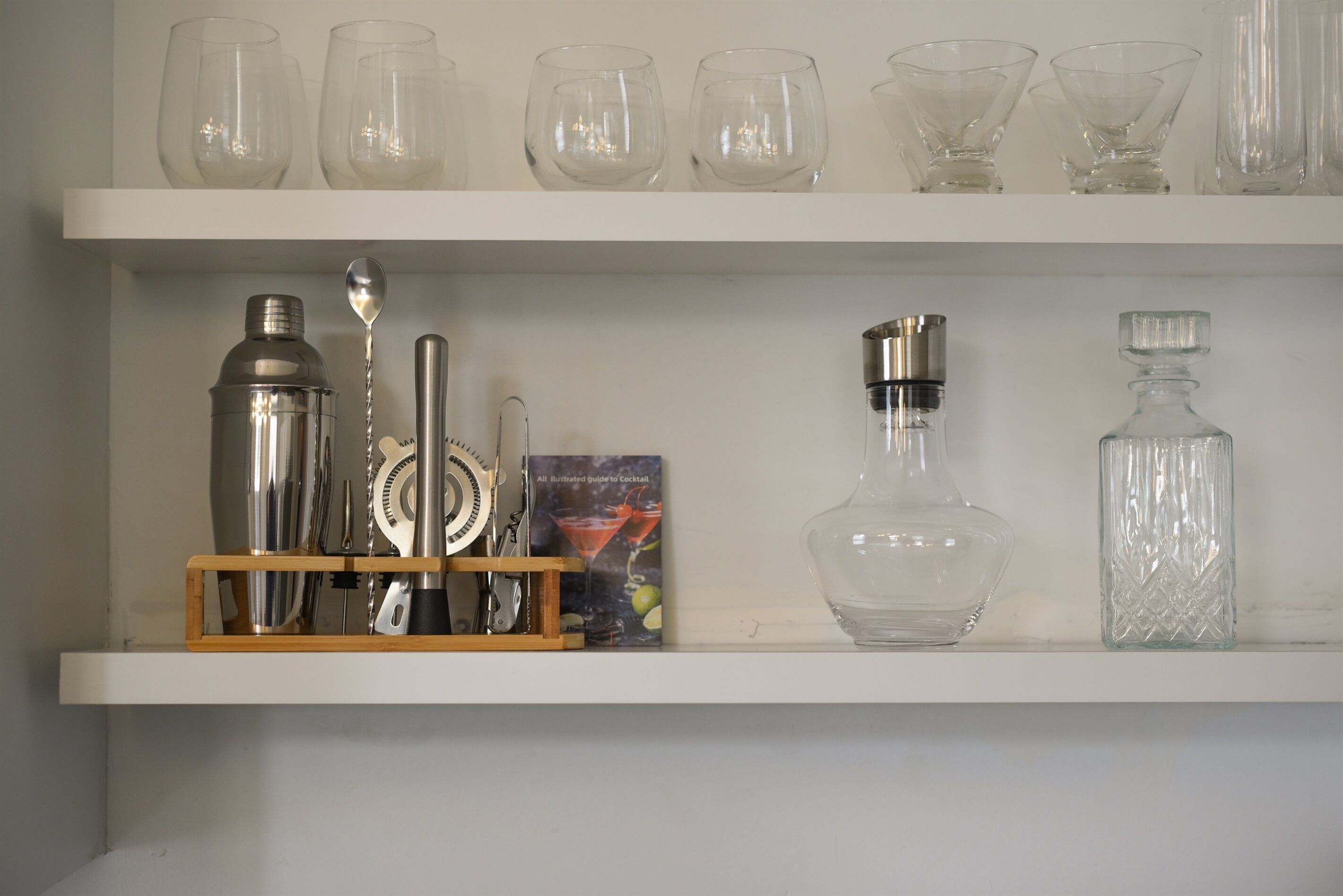 Uno scaffale con diversi bicchieri e strumenti per preparare cocktail.