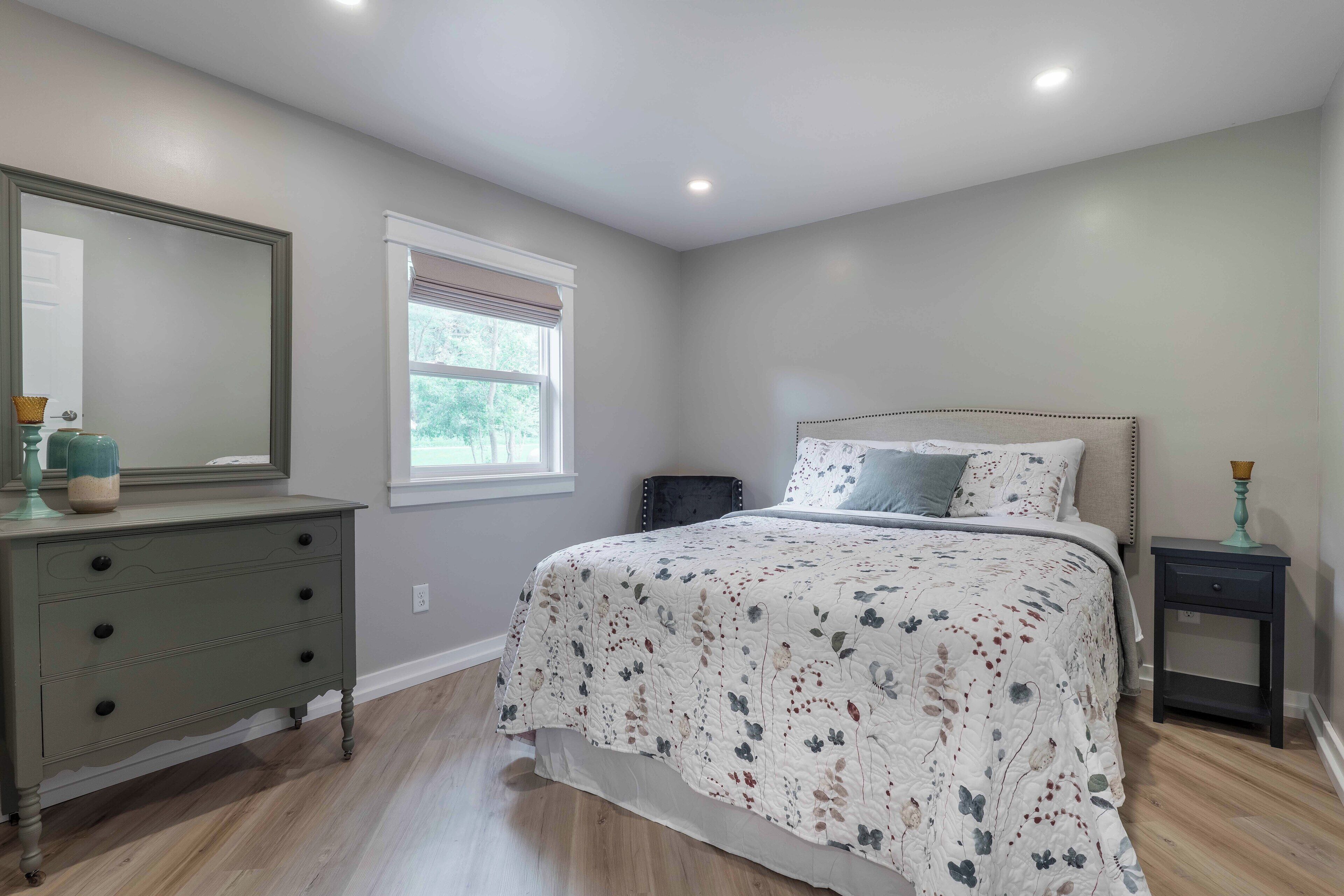 Une chambre à coucher avec un lit, une commode et une fenêtre.