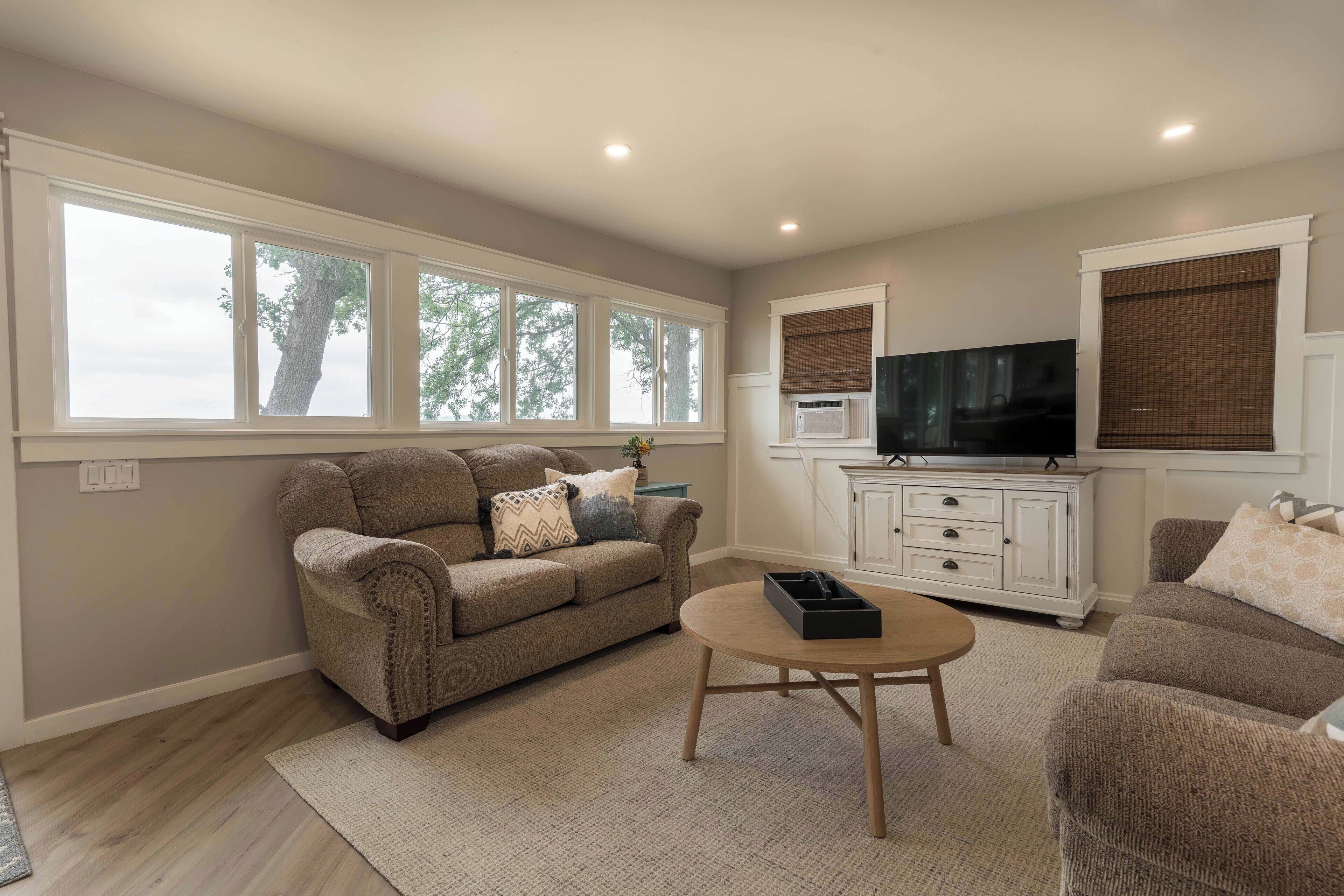 A living room with a beige sofa, a round coffee table, and a television on a white cabinet.