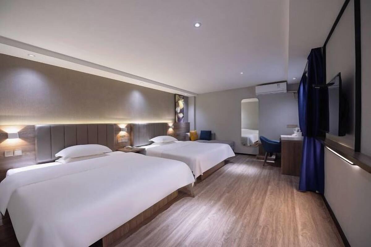 Hotellihuone, jossa on kaksi sänkyä, työpöytä, tuoli, televisio ja peili.