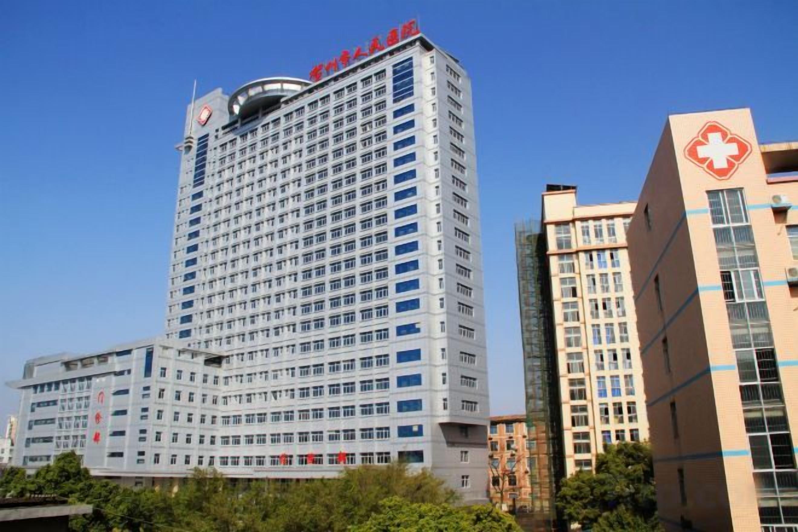 A multi-story building with a prominent red and white sign at the top, likely indicating a hospital or medical facility.