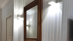 A hallway with a wooden console table, a large mirror, and a wall-mounted light fixture. - 1 minute from MAXIMAL POMPEII shopping center, 1 km from the excavations of Pompeii (Torre Annunziata)