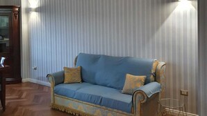A living room with a blue sofa, wooden floor, and striped wallpaper. - 1 minute from MAXIMAL POMPEII shopping center, 1 km from the excavations of Pompeii (Torre Annunziata)