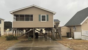 Ein zweistöckiges Haus mit einer Holzterrasse und einer Treppe, die zum oberen Stockwerk führt.