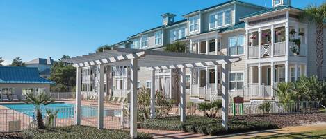 A two-story building with a covered outdoor seating area and a swimming pool.