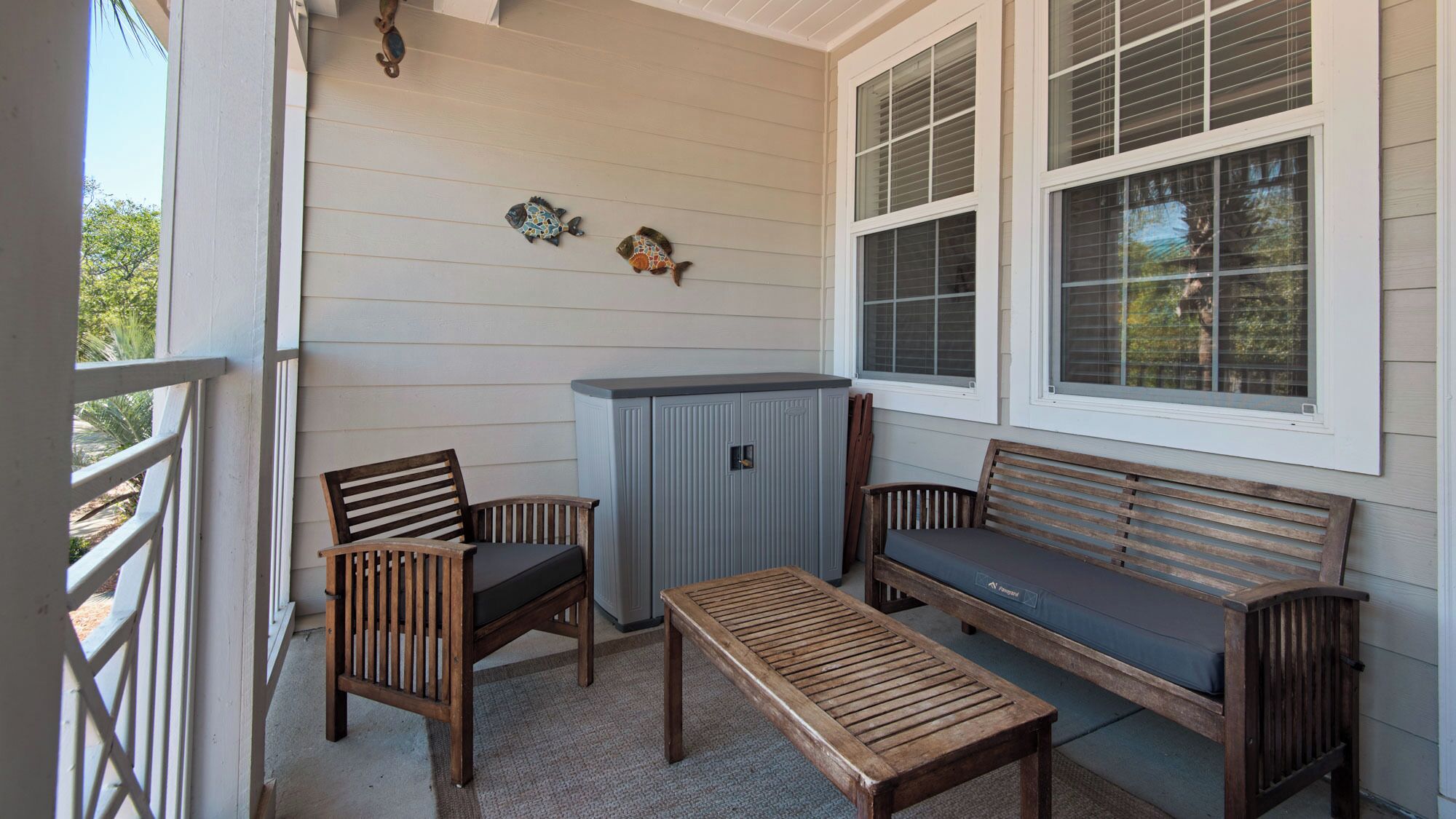 A covered porch with a wooden bench, two chairs, and a small table.