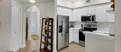 A modern kitchen with white cabinets, stainless steel appliances, and a central island.