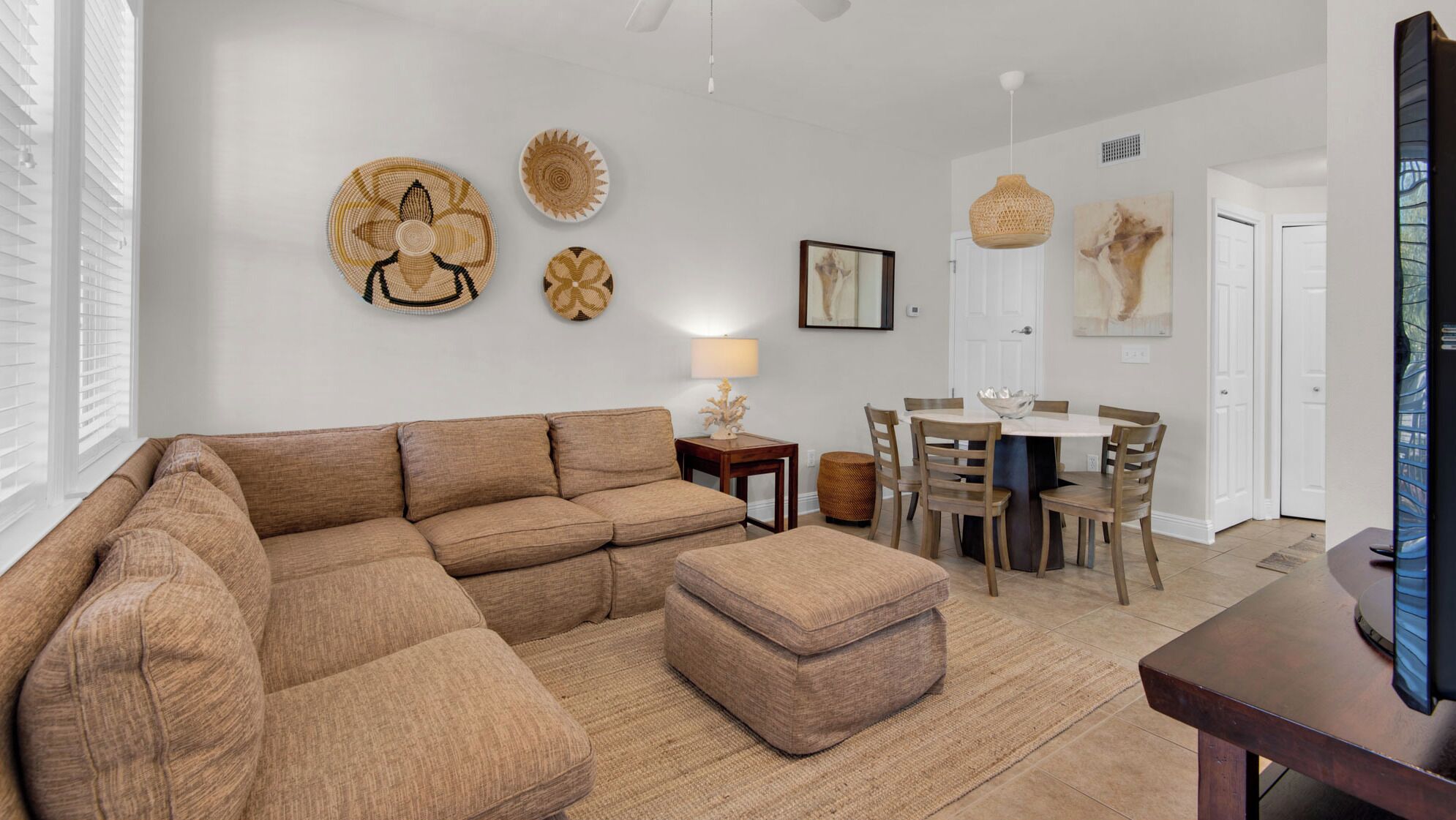 Una sala de estar con un sofá modular, una mesa de comedor con sillas y decoración en la pared.
