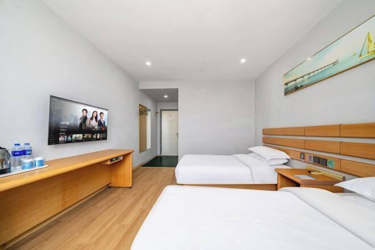 Habitación de hotel con dos camas, un escritorio de madera, un televisor de pantalla plana y un cuadro en la pared.