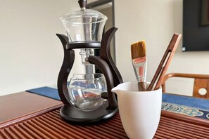 A coffee maker on a table with a cup and brushes. - Wanfenglin Hotel (Shanghai Heqing Meijiayi Plaza Branch) (Shanghai)