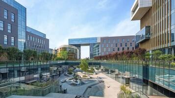 A modern building with a glass facade, a central courtyard with seating, and a bridge connecting different sections.
