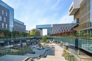 A modern building complex with glass facades, outdoor seating areas, and a central courtyard. - Wanfenglin Hotel (Shanghai Heqing Meijiayi Plaza Branch) (Shanghai)